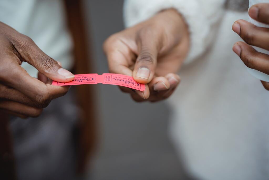 Crop faceless black people holding red small paper tickets