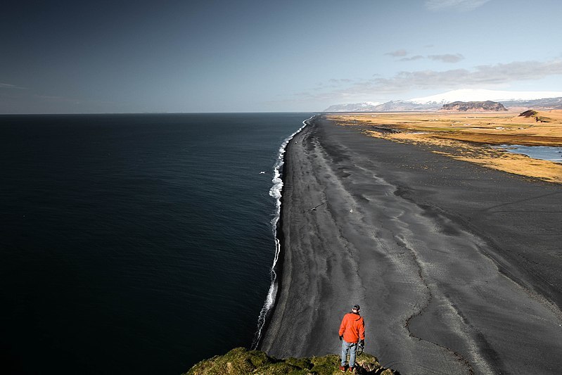 Man looking at black beach (Unsplash)
