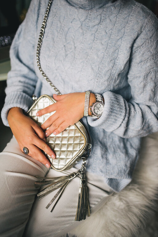 Close-up of young woman in light blue sweater with a fashionable small purse. Casual dress