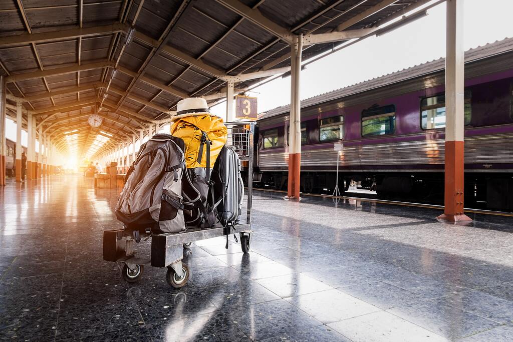 Several Bags on Trolley Near Train in Station