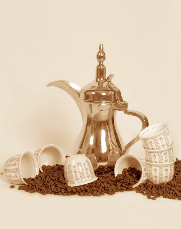 A dallah a traditional Arabic coffee pot with cups and coffee beans