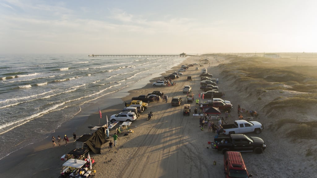 An aerial view of South Padre Island with people parked and driving on the beach