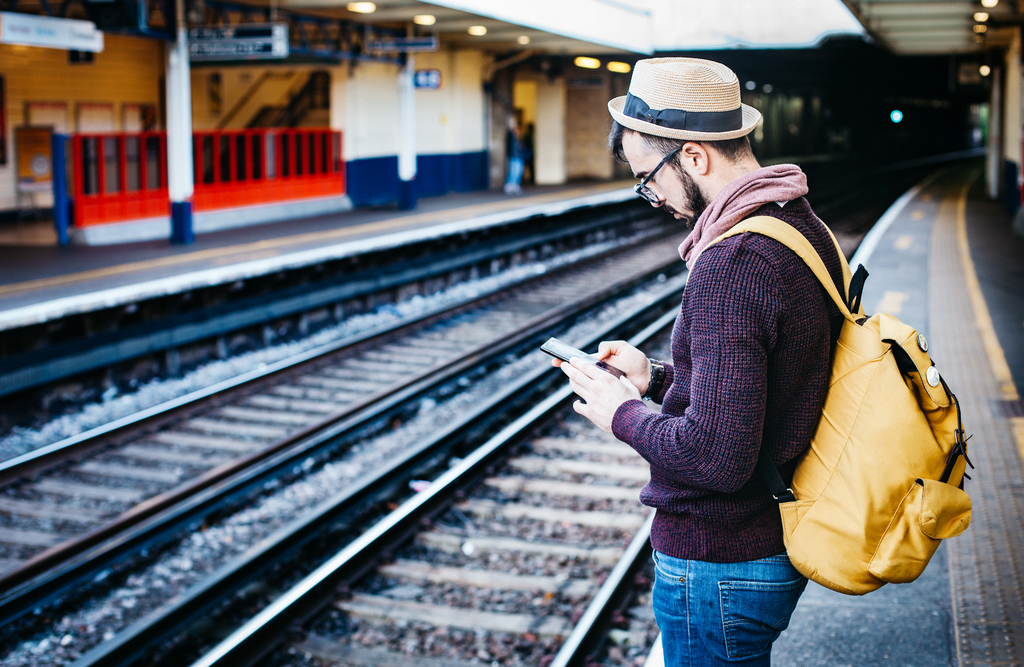 Man in hoodie standing in front of railway